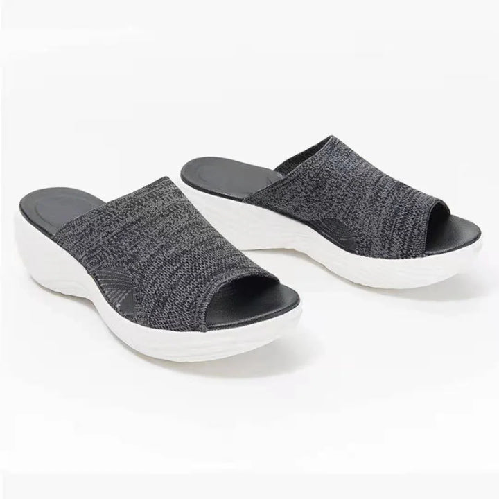 Black knit open-toe slip-on sandals with thick white wedge soles on white background