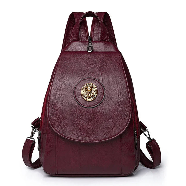 Burgundy leather backpack with gold emblem and adjustable shoulder straps