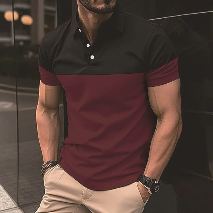 Man wearing a black and burgundy short-sleeve polo shirt with beige pants, standing outdoors
