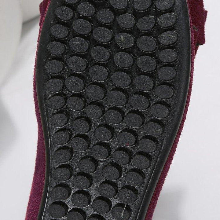 Close-up of black textured rubber sole with circular grip pattern on burgundy shoe