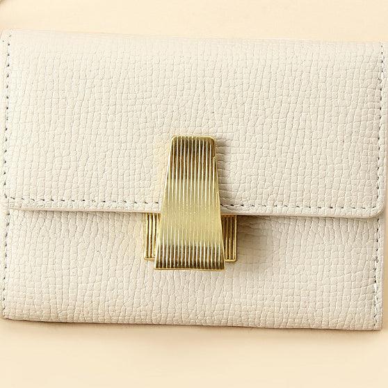 Close-up of beige textured leather wallet with a vertical ridged gold clasp