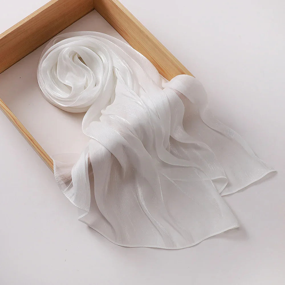 Soft white sheer chiffon scarf draped inside a wooden rectangular tray on white background