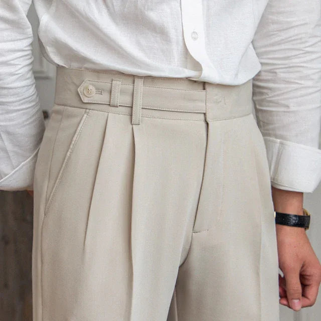 Close-up of beige high-waisted pleated trousers with side pockets and a white button-up shirt