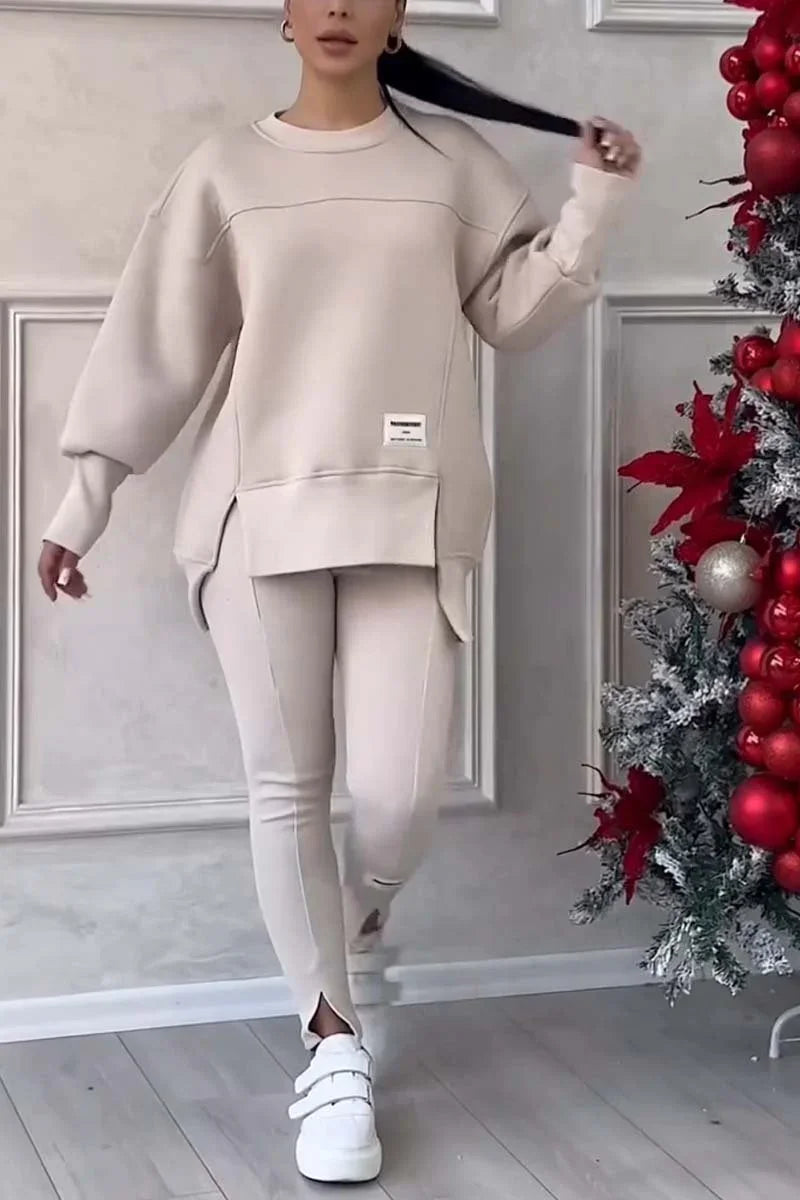 Woman wearing beige oversized sweater and leggings with white sneakers near decorated Christmas tree