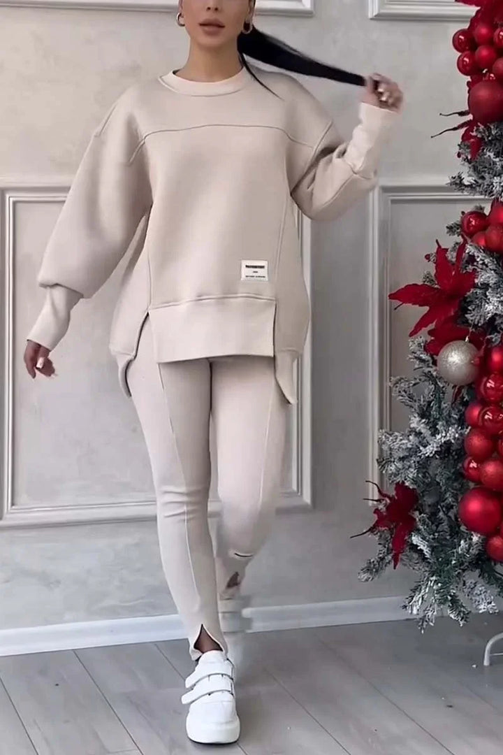 Woman wearing beige oversized sweater and leggings with white sneakers near decorated Christmas tree
