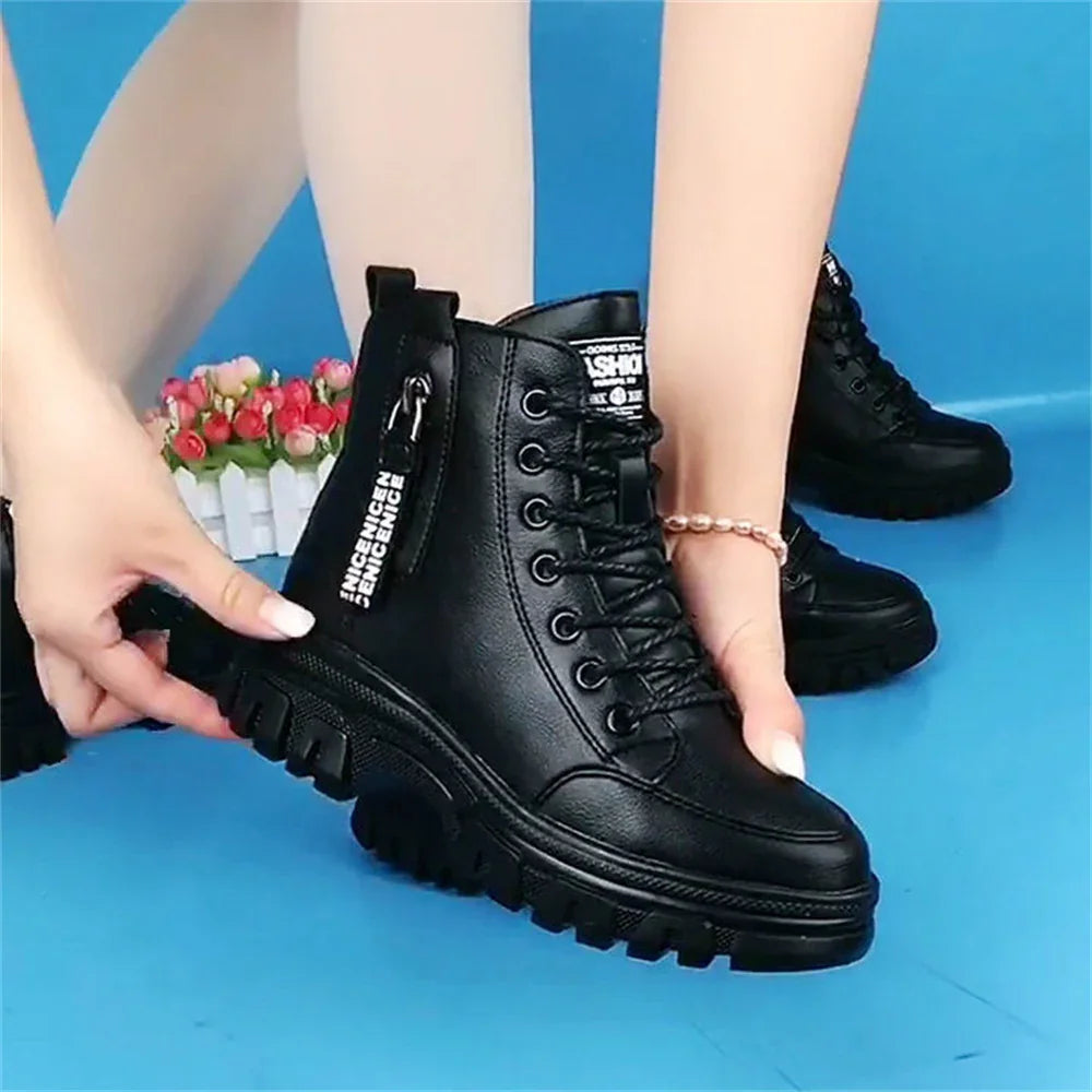 Black chunky lace-up ankle boots with thick tread sole on blue background