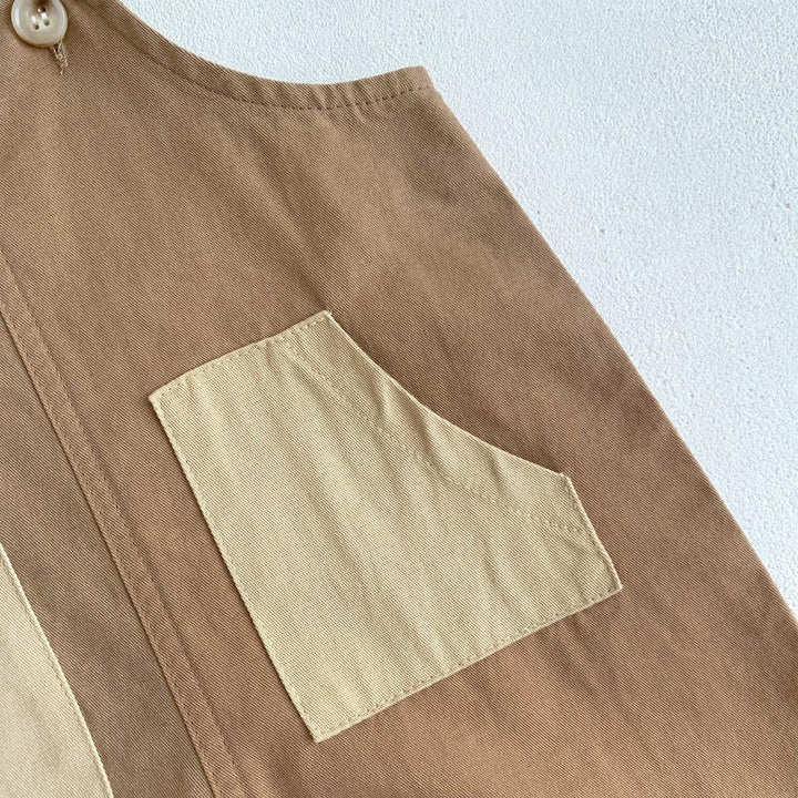 Close-up of beige and brown cotton fabric with a contrasting small pocket and button detail