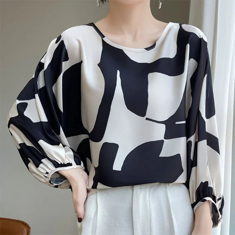 Woman wearing black and white abstract pattern blouse with balloon sleeves and white pants