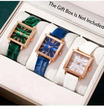 Set of three square rose gold watches with green, blue, and white leather straps in a display box