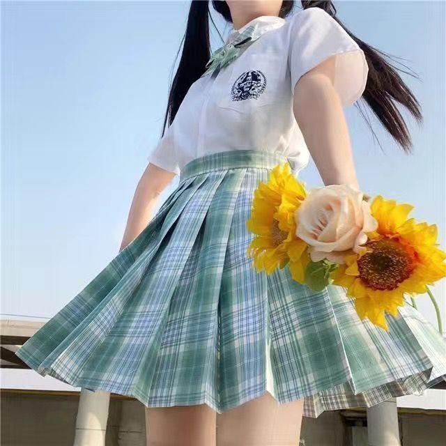 Young woman in white blouse and green plaid skirt holding sunflowers and a light pink rose outdoors