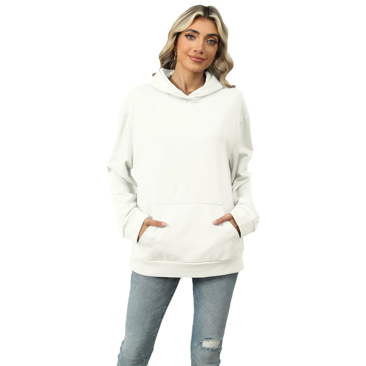 Smiling woman wearing white hoodie with front pocket and light blue ripped jeans on white background