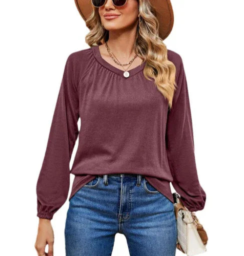 woman wearing plum long sleeve top paired with blue jeans, sunglasses, and a brown hat