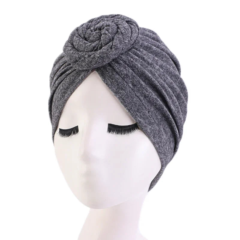 gray fabric turban headwrap with rose detail on white mannequin head