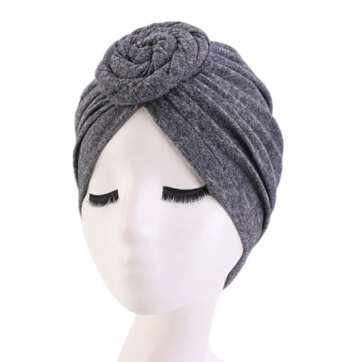 gray fabric turban headwrap with rose detail on white mannequin head