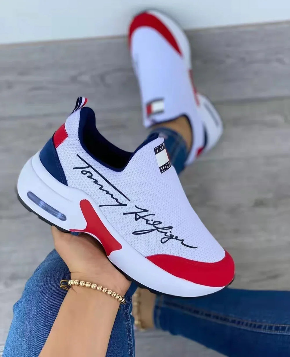 White Tommy Hilfiger slip-on sneakers with red and navy accents, breathable mesh design