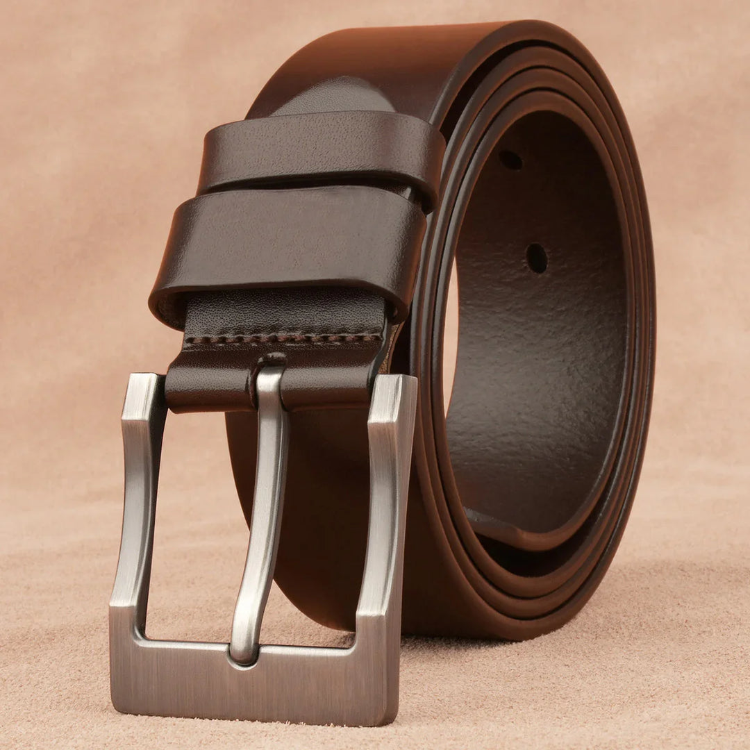 Close-up of a rolled dark brown leather belt with a matte silver buckle on beige background