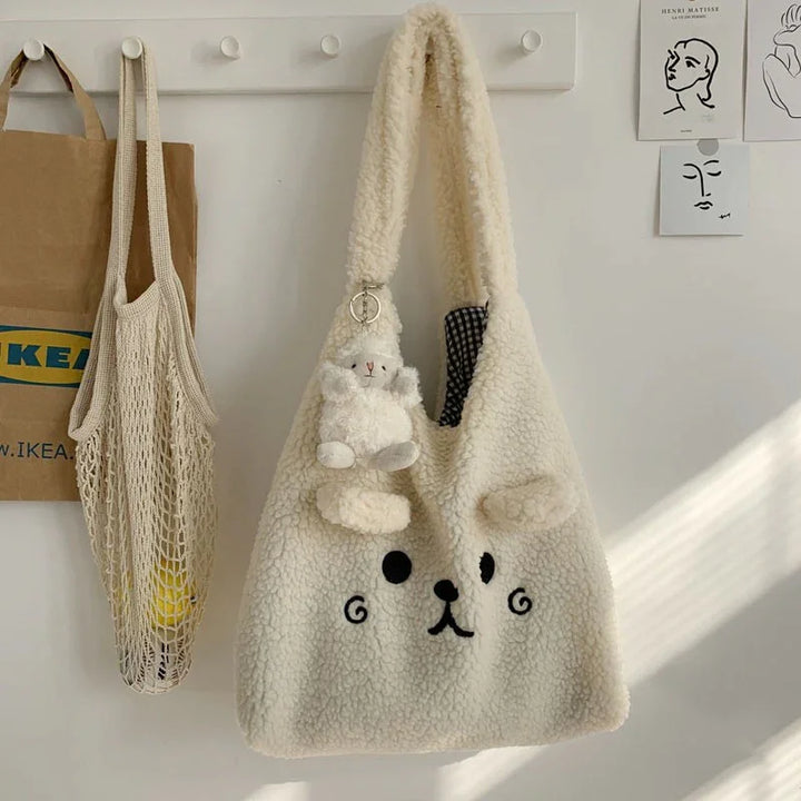 Cozy cream-colored teddy bear fleece tote bag with plush bear keychain hanging on white wall hooks