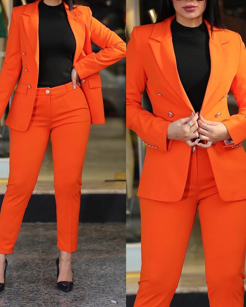 Woman wearing a bright orange suit with tailored blazer and pants, paired with black top and black heels