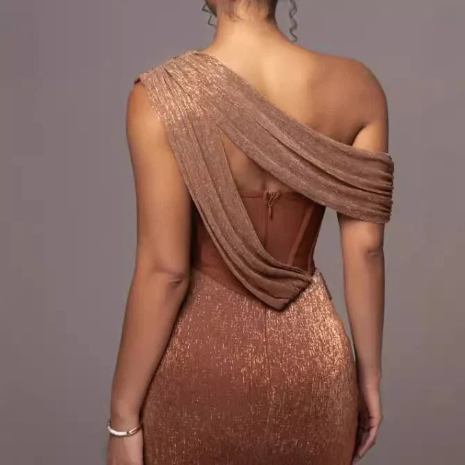 Back view of woman wearing a shimmery copper-brown one-shoulder evening gown with draped fabric