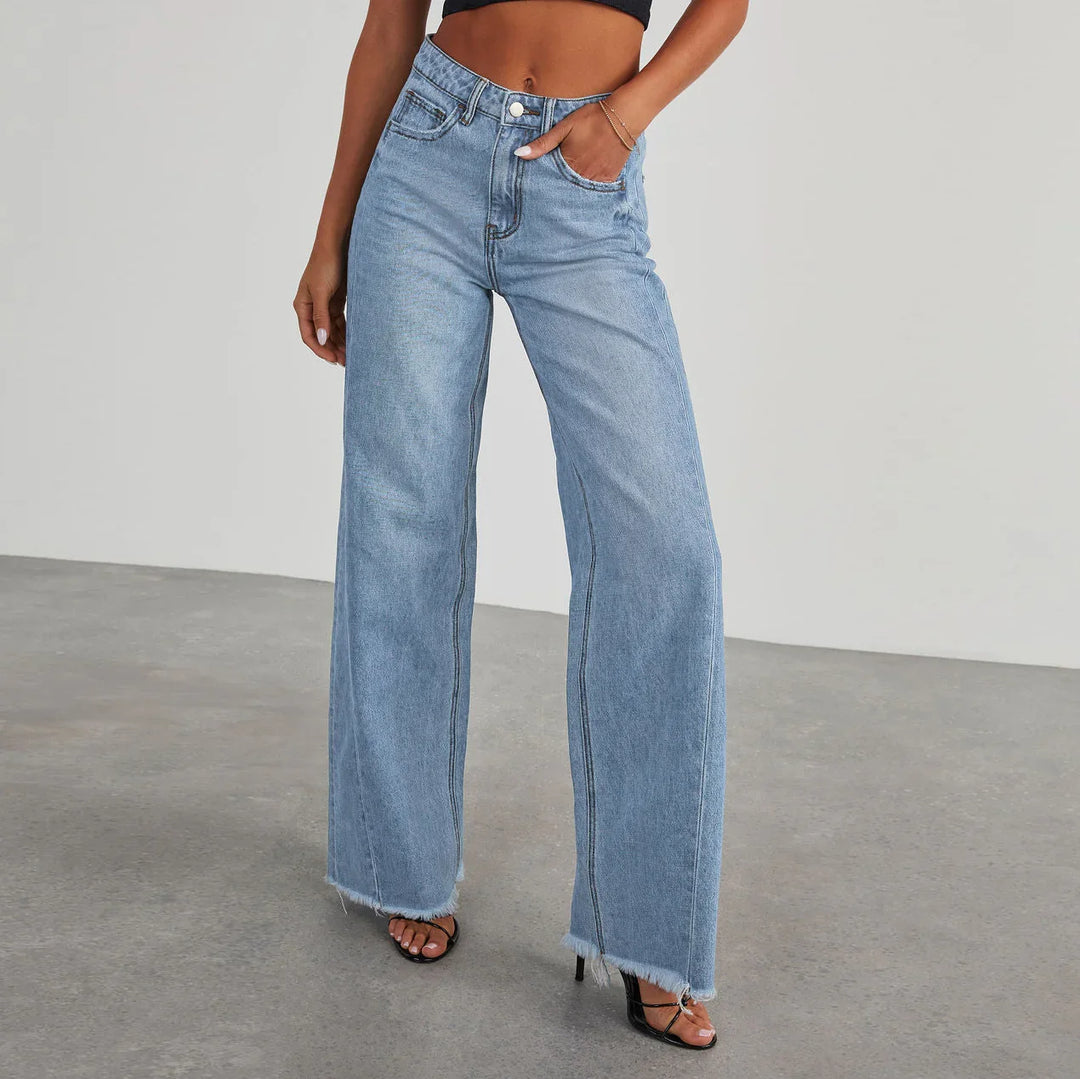 Woman wearing light blue high-waisted wide-leg jeans with raw hem and black heeled sandals