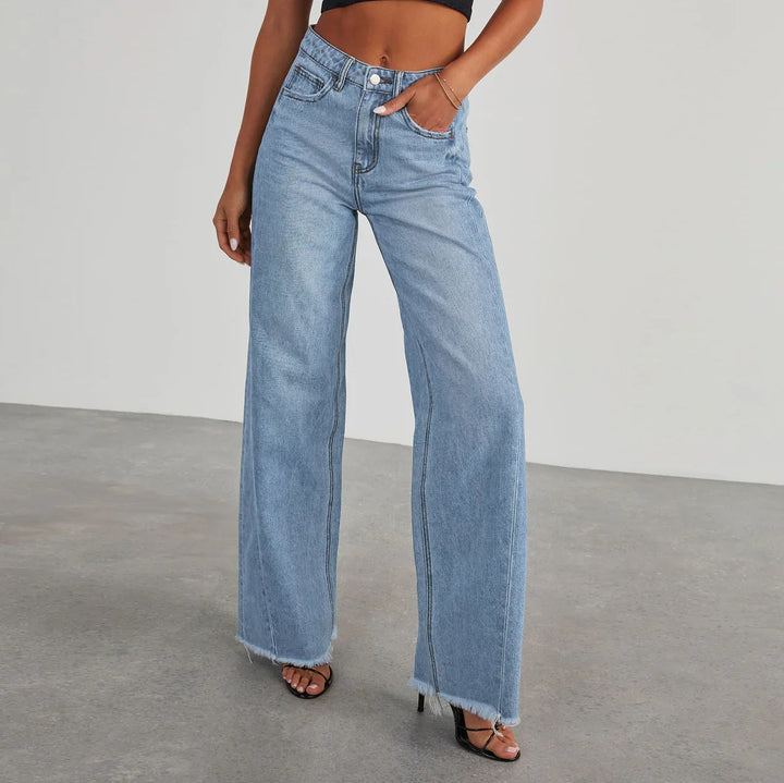 Woman wearing light blue high-waisted wide-leg jeans with raw hem and black heeled sandals