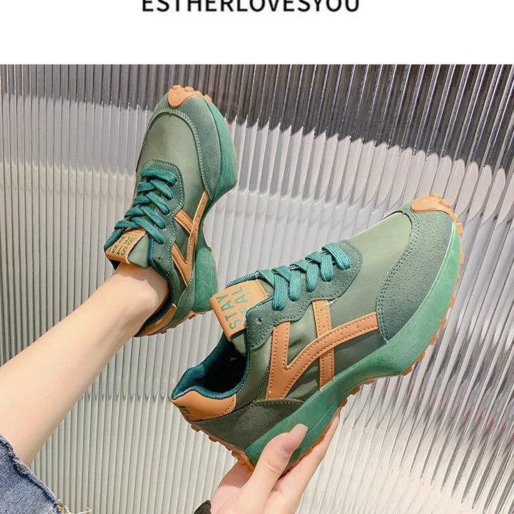 Green and tan casual sneakers with teal laces worn on feet against a ribbed metallic background