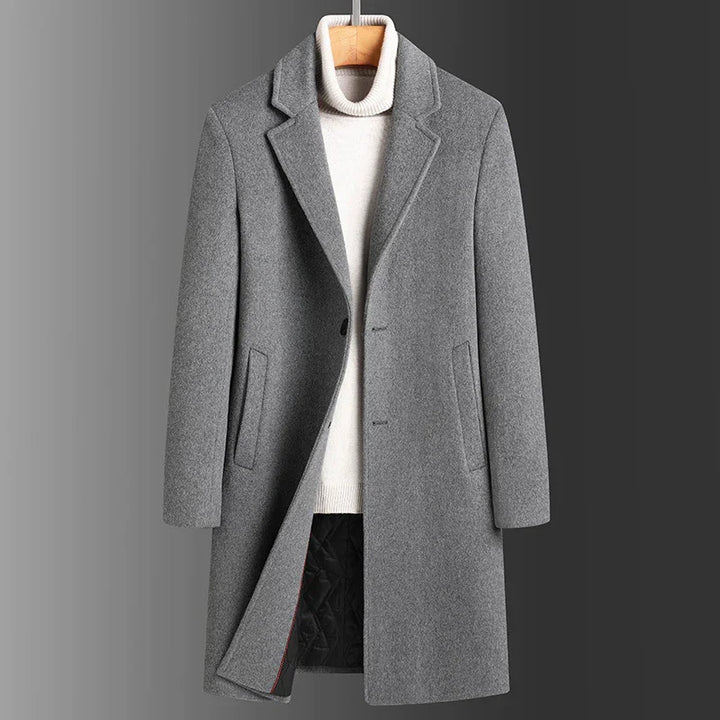 Gray wool men's overcoat with lapel collar and side pockets over white turtleneck sweater