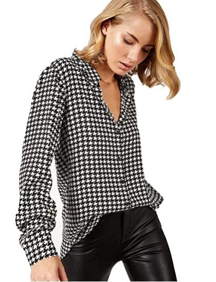 Woman wearing black and white houndstooth blouse and black leather pants on white background
