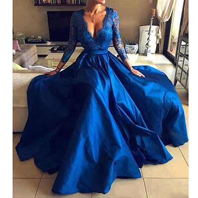 Woman wearing elegant royal blue evening gown with lace sleeves sitting on beige sofa indoors