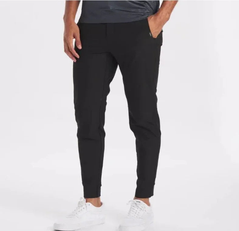 Man wearing black slim-fit jogger pants with side pockets and white sneakers on a white background