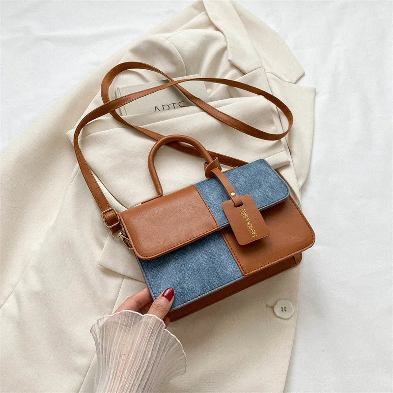 Brown and denim patchwork handbag with top handle and shoulder strap on beige blazer