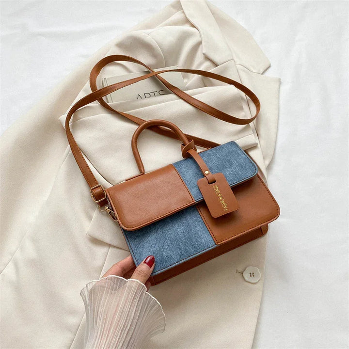 Brown and denim patchwork handbag with top handle and shoulder strap on beige blazer
