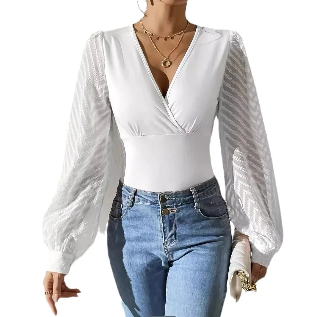 Woman wearing white V-neck bodysuit with sheer patterned puff sleeves, blue jeans, and gold necklaces