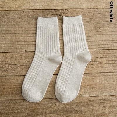 Pair of off-white ribbed crew socks laid flat on wooden surface