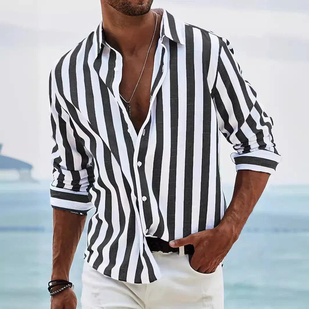 Man wearing black and white vertical striped shirt with rolled-up sleeves by the seaside