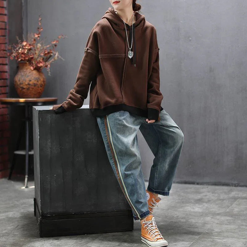 Woman wearing brown hoodie with striped loose jeans and yellow high-top sneakers sitting indoors