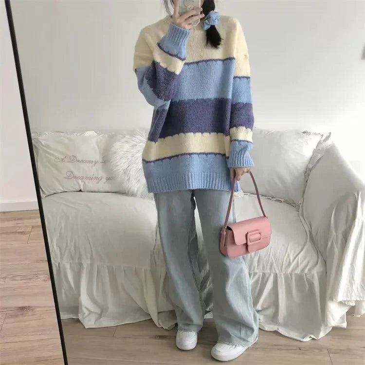 Woman wearing cozy oversized striped sweater in blue and cream with loose light jeans and pink handbag