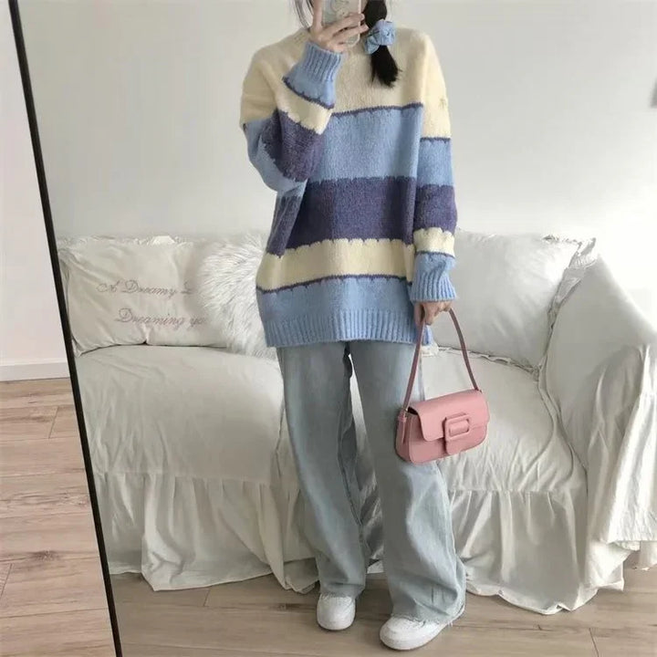 Woman wearing cozy oversized striped sweater in blue and cream with loose light jeans and pink handbag