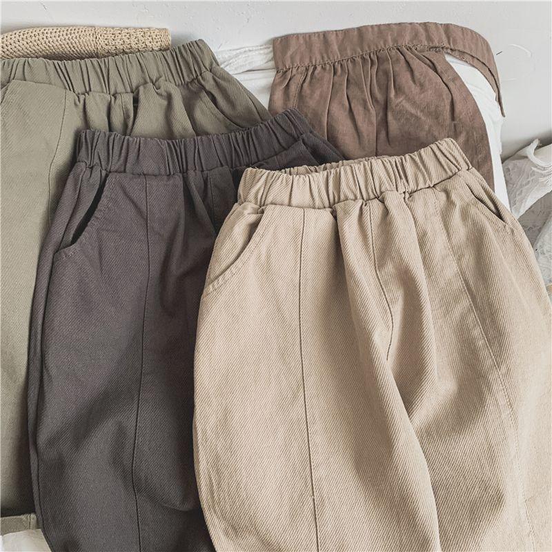 Folded cotton casual pants in beige, brown, and gray with elastic waistbands on a white surface