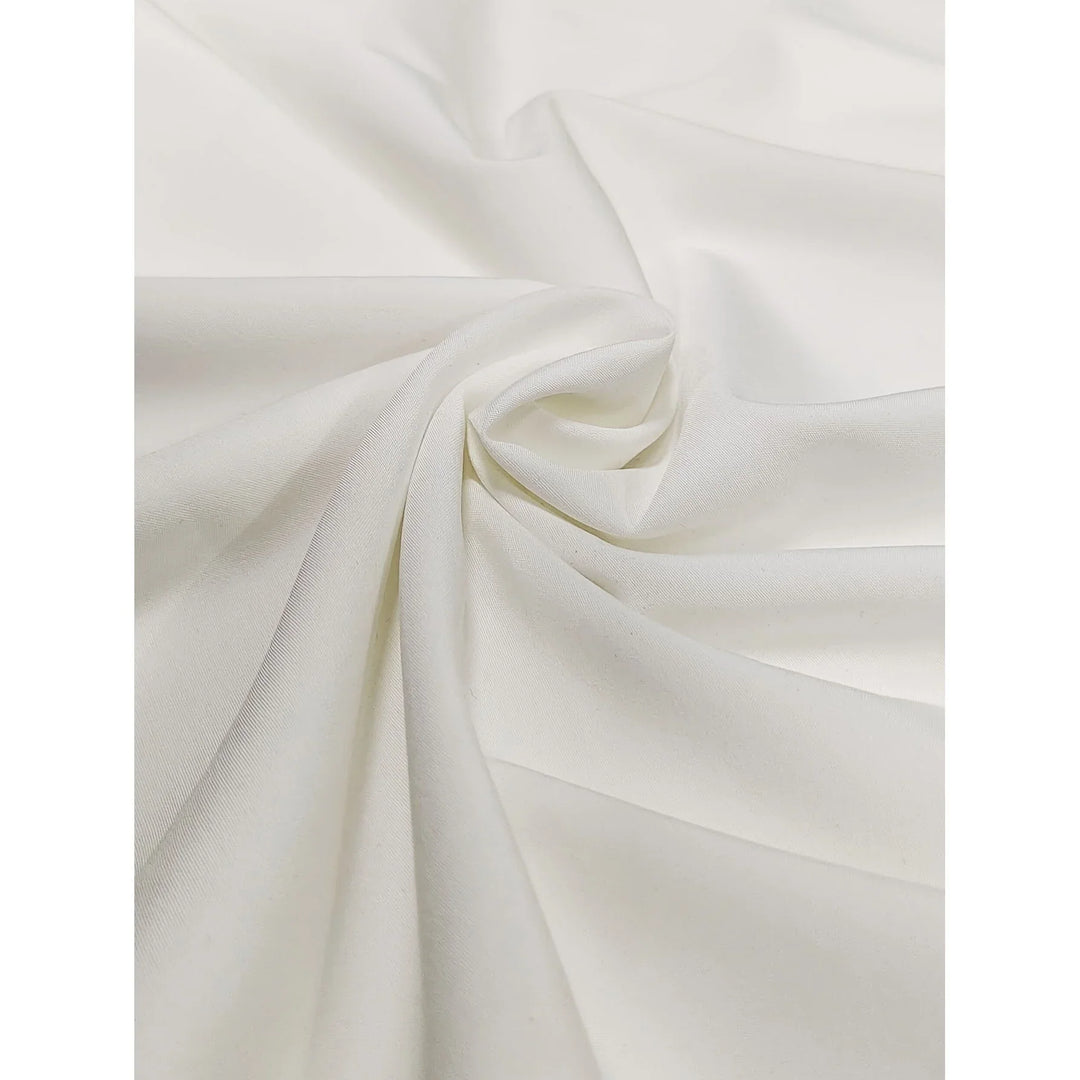 Close-up of soft cream-white fabric with smooth, draped texture and subtle folds
