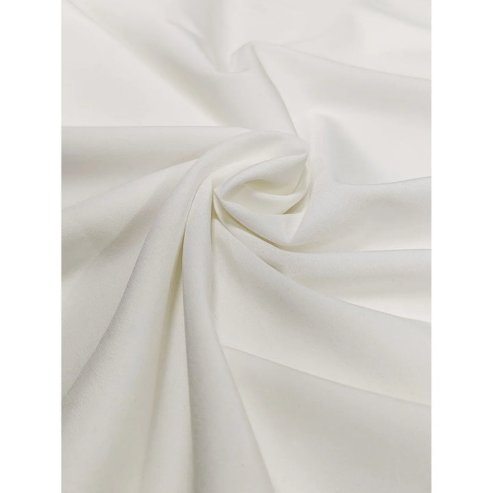 Close-up of soft cream-white fabric with smooth, draped texture and subtle folds