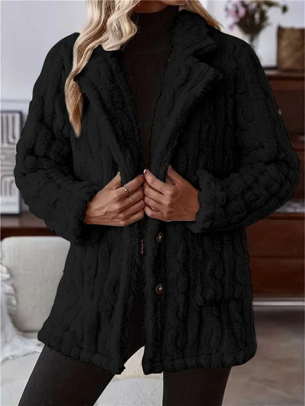 Woman wearing black textured button-up fuzzy jacket with pockets and long sleeves in indoor setting