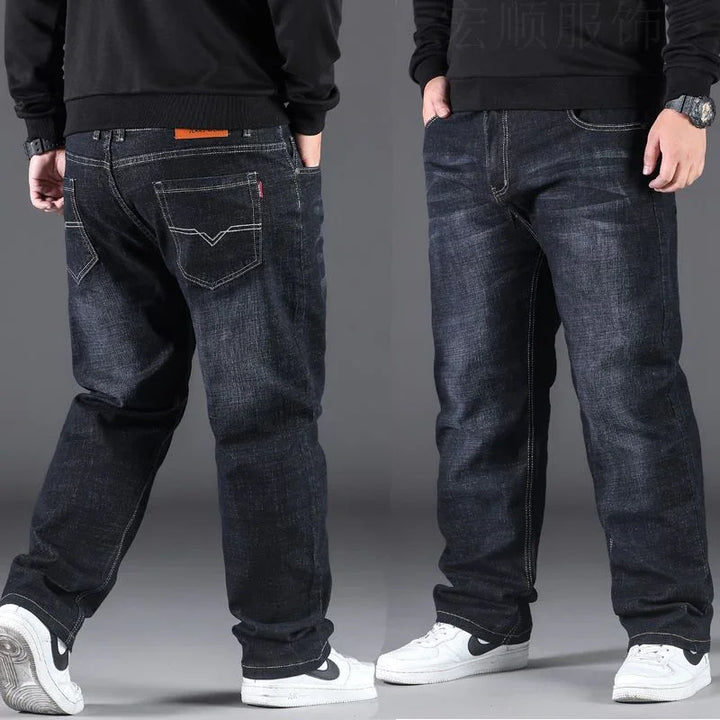 Front and back view of man wearing dark washed relaxed fit jeans with white sneakers and black sweatshirt