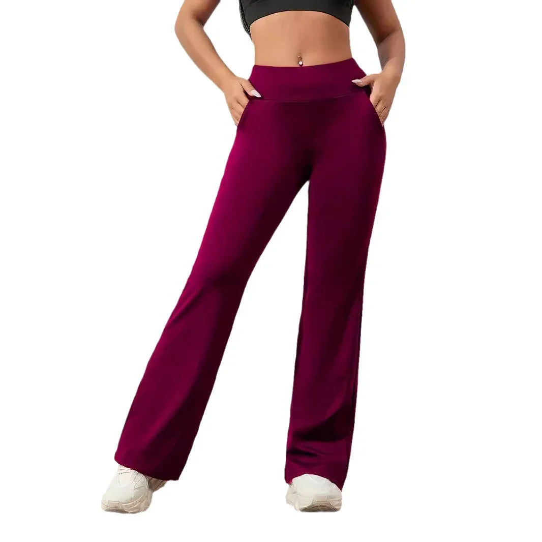 Woman wearing high-waisted burgundy flared pants with side pockets and white sneakers
