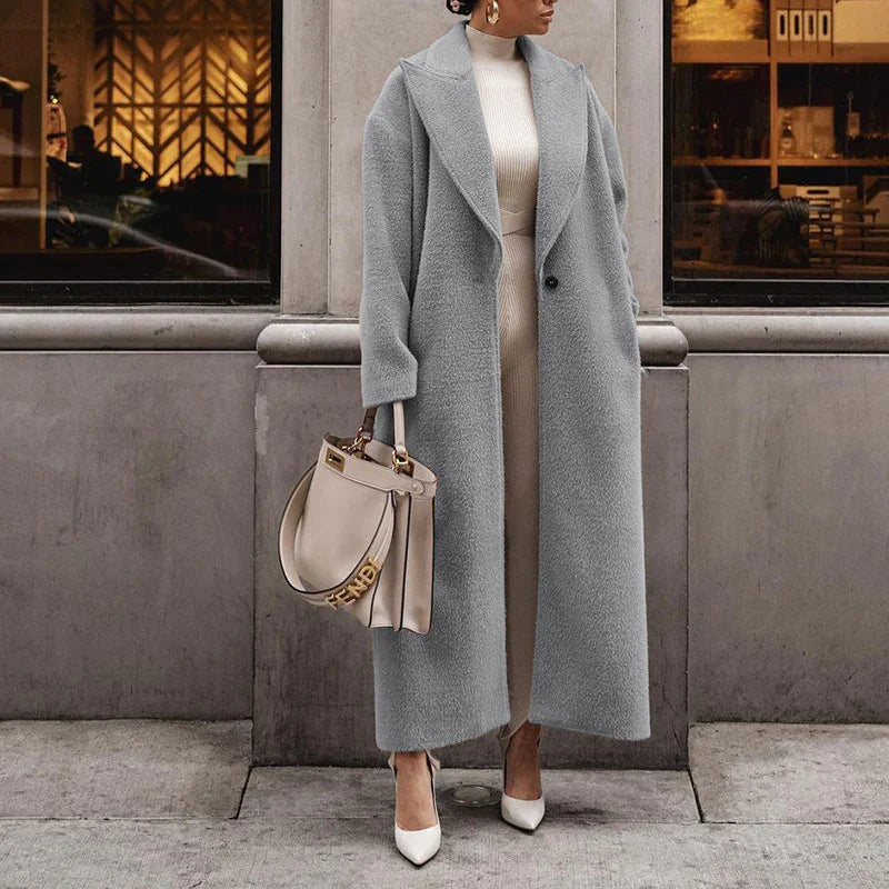 Woman wearing long gray teddy coat, cream knit dress, white heels, and holding beige Fendi handbag on city street