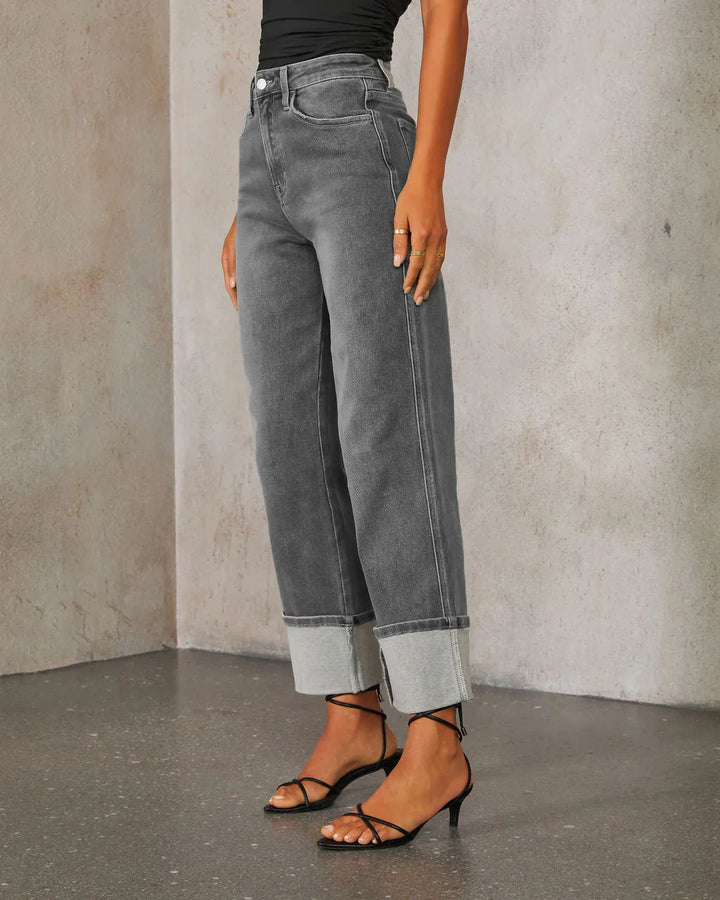 Women's high-waisted gray cuffed jeans paired with black strappy heels and a black top