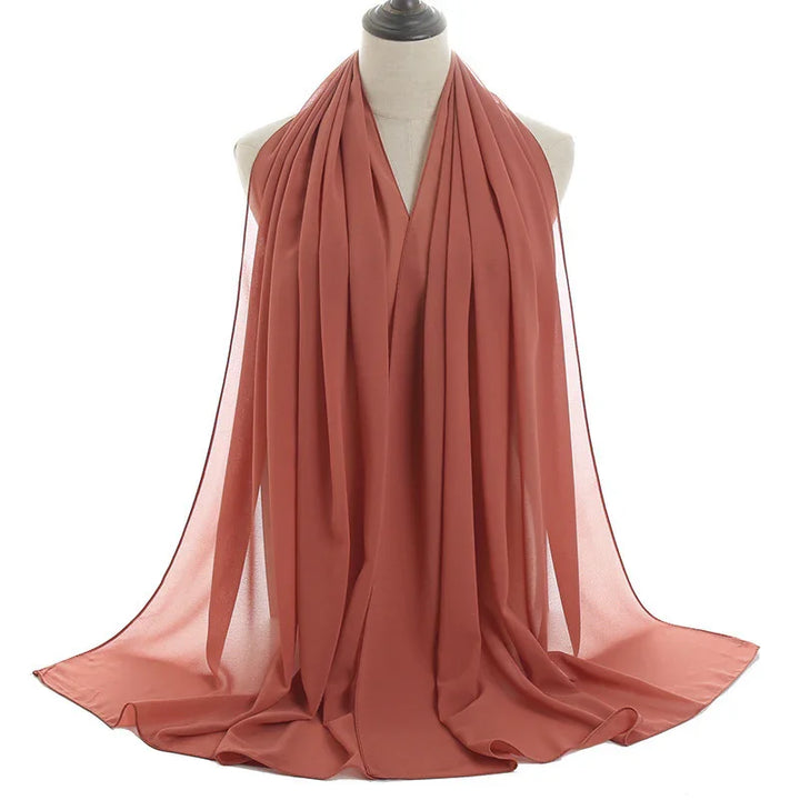 Lightweight rust orange chiffon scarf displayed on a white mannequin bust
