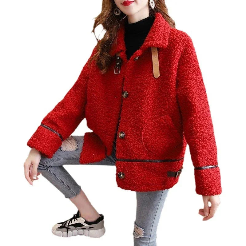 Woman wearing red teddy coat with button details and distressed grey jeans crouching