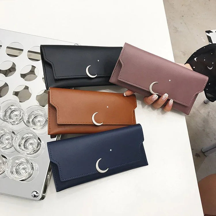 Four stylish leather wallets in black, mauve, brown, and navy with crescent moon and star embellishments