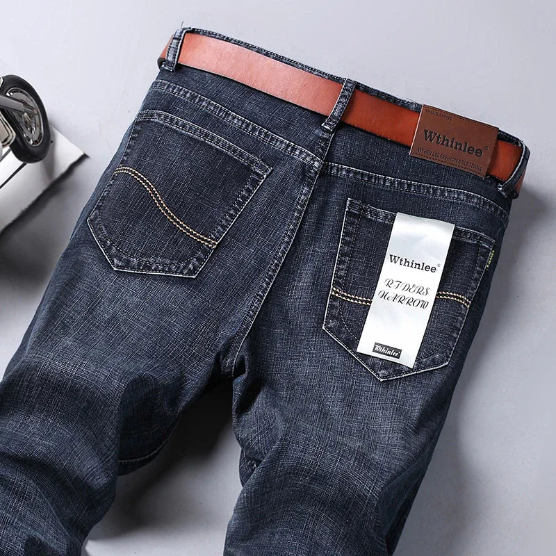 back view of dark blue denim jeans with brown belt and Wthinlee brand label on pocket